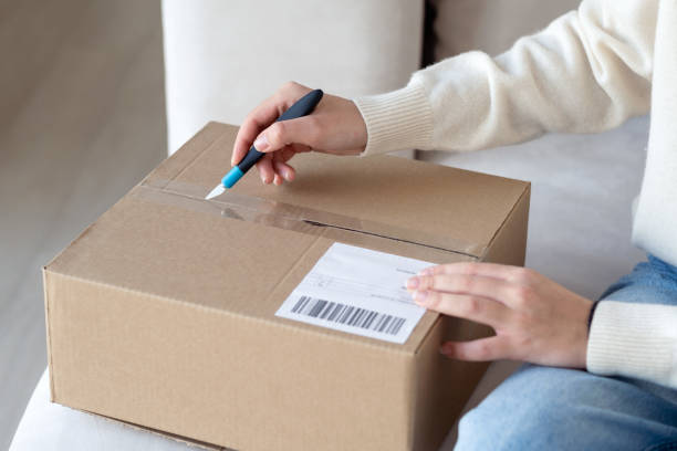 istock A young woman opens a box with a purchase from an online store. 1385369692