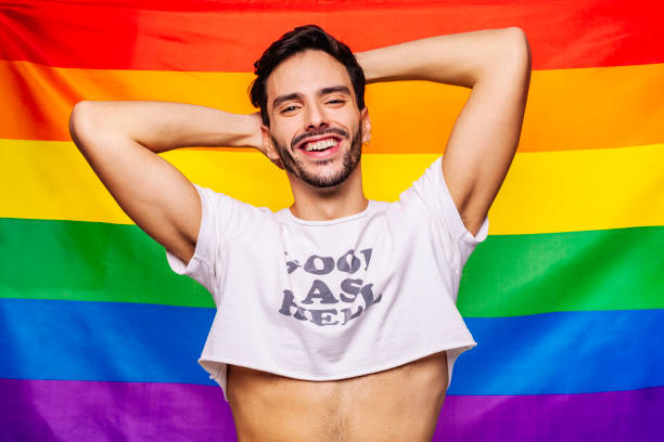 istock Happy gay man putting hands behind head over rainbow flag background 1385371796