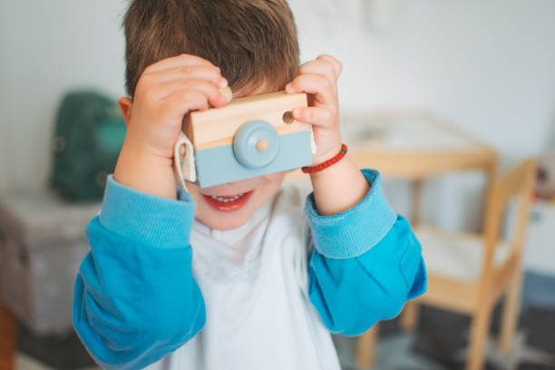 Cute toddler boy playing with toy camera