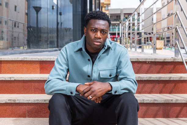 istock Confident ethnic guy sitting on stairs on street 1385379905