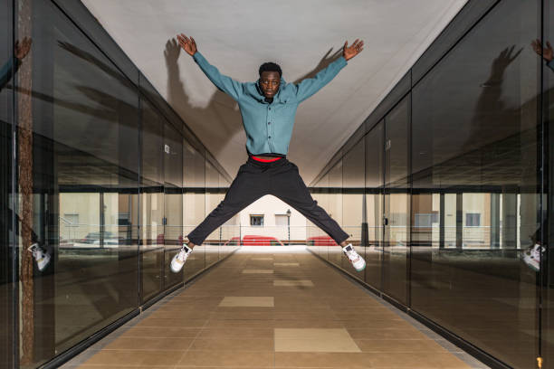 istock Trendy serious black man jumping in passage and looking at camera 1385379930