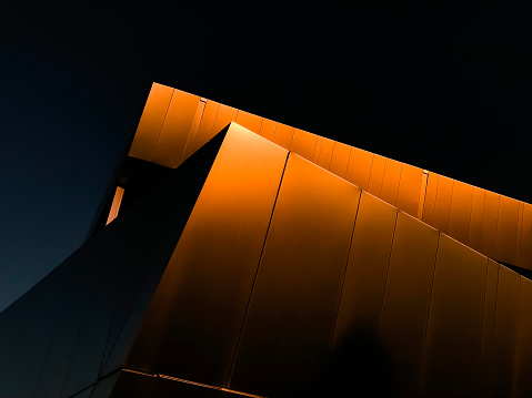 An ethereal abstract image shot at the golden hour of the metal facade architecture of a modern building.  There are lines and angles moving through this high-contrast image. The image features a close up of an office building in Miamisburg Ohio