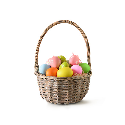 Easter wicker basket with pastel colorful eggs decorated isolated on white background. Festive Christianity religion tradition.