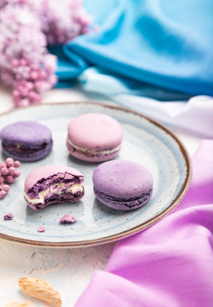 istock Purple macarons or macaroons cakes with cup of coffee on a white concrete background. Side view, selective focus. 1385389024