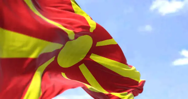 Detail of the national flag of North Macedonia waving in the wind on a clear day. North Macedonia is a country in Southeast Europe. Selective focus.