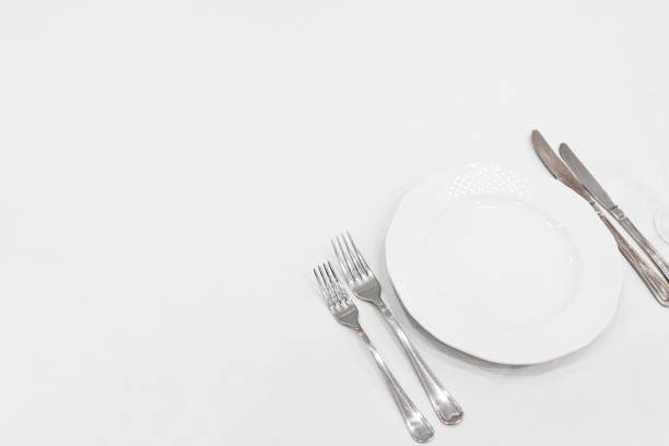 istock empty white plate with two forks and two knives. lots of empty space 1385390717