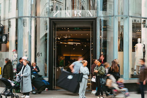 London, UK - 14 March, 2022: wide angle image depicting the exterior of a Zara clothing store in central London, with blurred motion of people walking past on the street outside the shop.