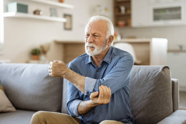 älterer mann mit ellenbogenschmerzen - acute pain stock-fotos und bilder