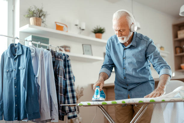 istock Senior Man Listening to Music while Ironing 1385395761