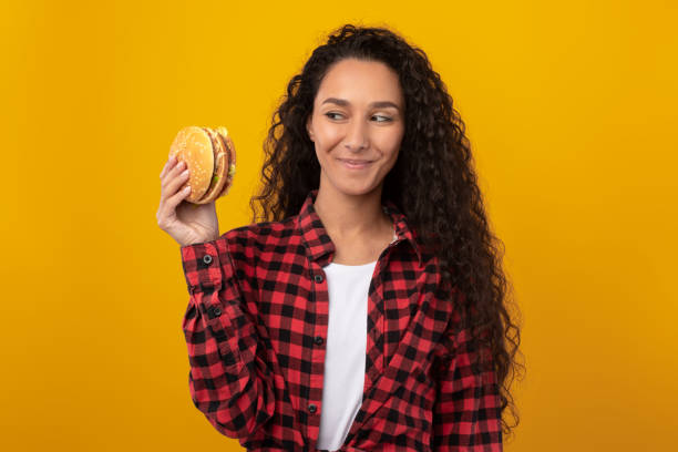 istock Smiling Casual Lady Holding Burger At Studio 1385399147