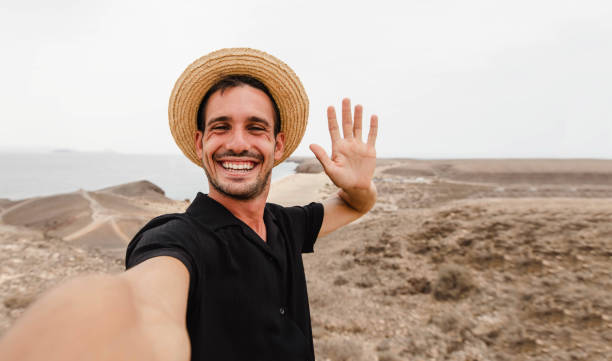 Handsome young man taking selfie picture outside - Happy guy showing something on empty hand receiving or giving gesture stock photo