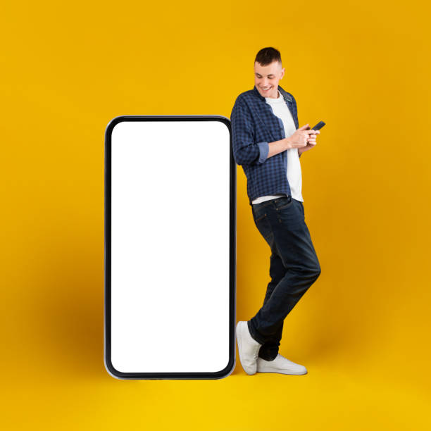 istock Man Near Big Cellphone Standing Using Phone On Yellow Background 1385400592