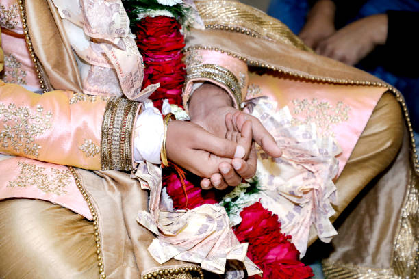 istock Indian groom performing rites holding some rice in his mehndi designed hands during wedding ceremony. 1385402586