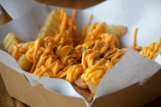 Close-up of french fries and cheese in a small cardboard container. popular among teenagers