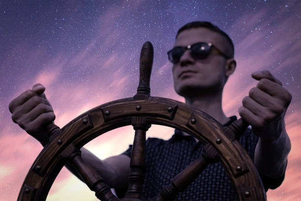 istock A man controls the yacht, hands on the steering wheel, handwheel on sky background 1385407332