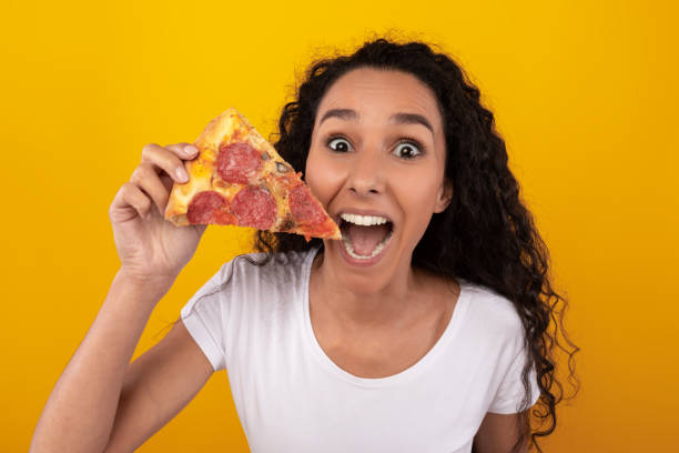 istock Happy Latin Lady Holding Pizza Slice At Studio 1385407412