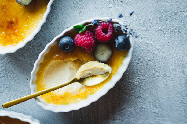 Closeup of partially eaten creme brulee dessert. Delicious dessert consists of a rich custard with hardened layer of caramelized sugar, garnished with blueberries, raspberries, and mint lives.