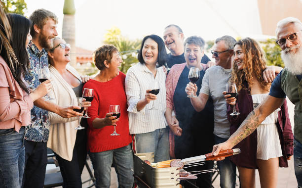 multi generational friends having fun at barbecue dinner outdoor - focus on chef hand holding meat - dining senior adult friendship mature adult imagens e fotografias de stock