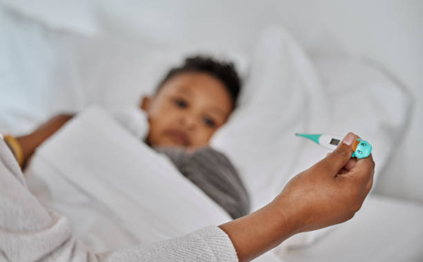 istock Shot of an unrecognizable parent checking a sick boy's temperature at home 1385408443