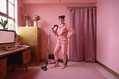 Full length portrait of woman cleaning pink home interior