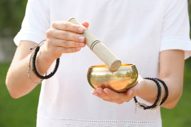 istock Woman using singing bowl in sound healing therapy outdoors, closeup 1385411810