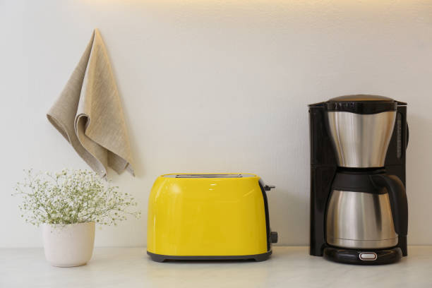 istock Modern toaster, coffee machine and flowers on counter in kitchen 1385415028