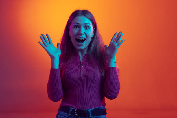istock One emotional young beautiful posing isolated on orange background in neon light, filter. Concept of emotions, music, beauty 1385415593