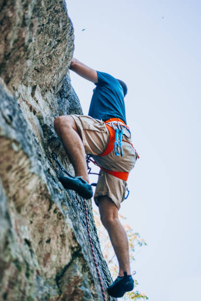 istock Male rock climber clings to a cliff 1385418417