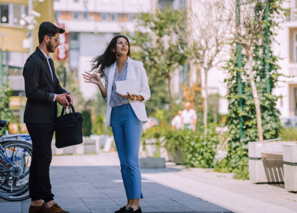 istock Smiling businessman with suitcase sharing ideas with colleague during stroll 1385421051