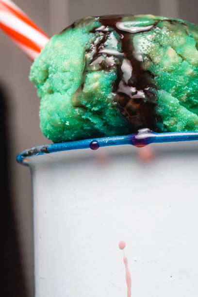 Close-up of a cup with mint ice cream and strawberry syrup.
