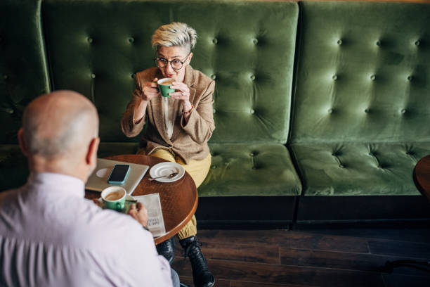 Mature woman talking to a mature man in cafe, the are having coffee together.