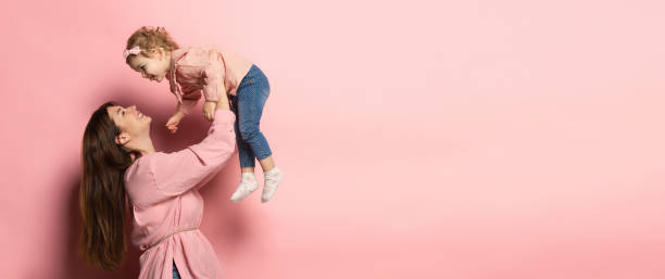 遊ぶ。若い女性と少女、母と娘の肖像画は、ピンクのスタジオの背景に隔離されています。母の日のお祝い。家族、子供時代、母性の概念 - isolated little girls two people child ストックフォトと画像