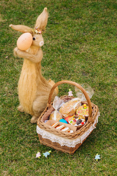 Easter basket with ukrainian easter cake, cookies and Easter eggs on green lawn. Easter bunny figure stock photo