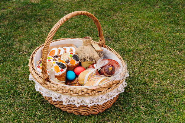Easter basket with ukrainian easter cake, cookies and Easter eggs on green lawn, space for text. Easter item stock photo