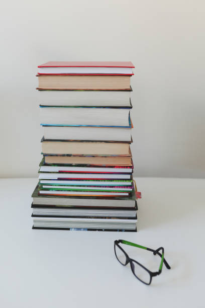 istock Stack of books with eyeglasses on a table on white background. home education and study concept 1385434641