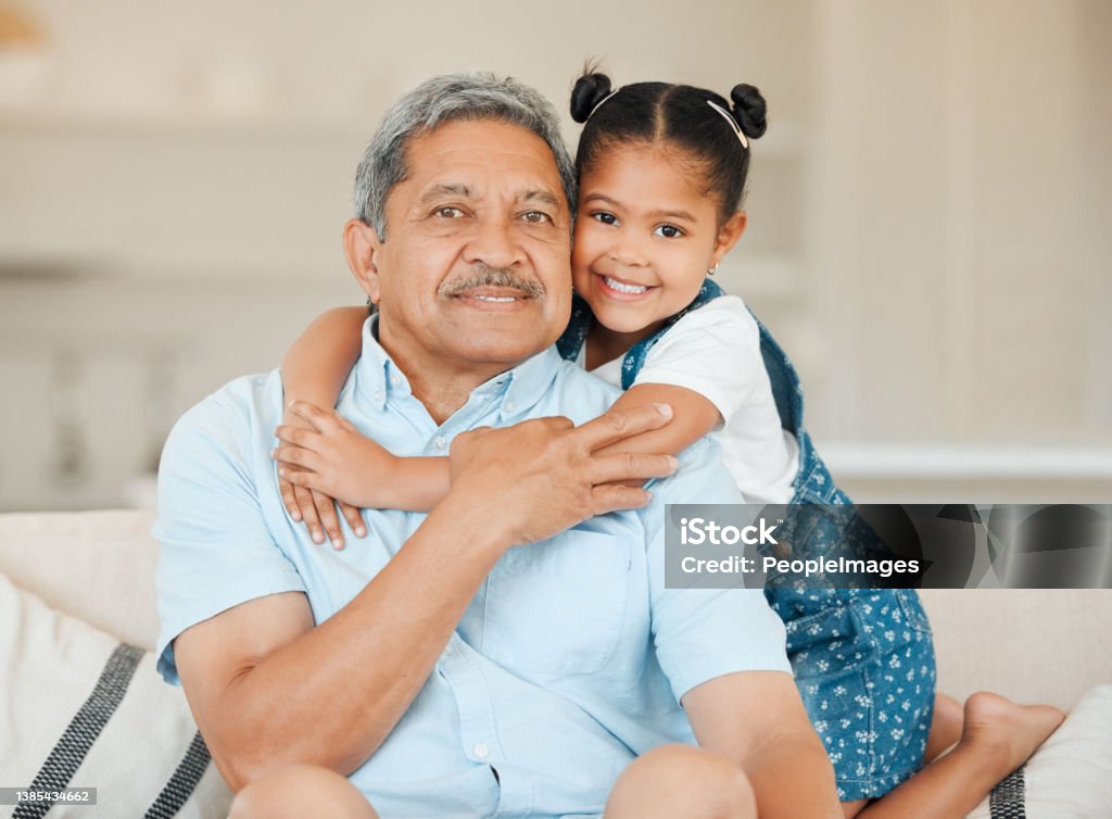 Shot of a grandfather and granddaughter bonding on the sofa at home There is no doubt that it is around the family Grandparent Stock Photo