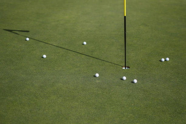 A close up of golf balls around the pin on a green stock photo
