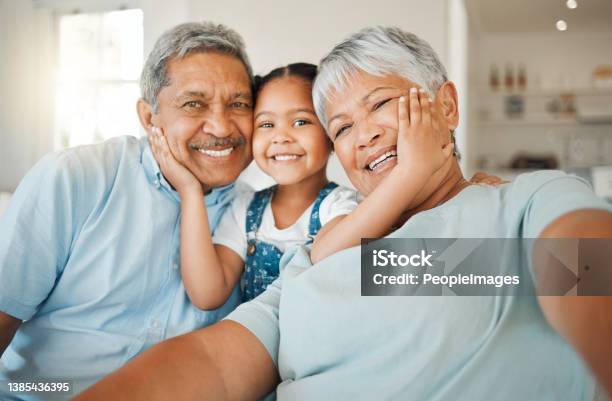 Shot Of Grandparents Bonding With Their Granddaughter On A Sofa At Home Stock Photo - Download Image Now