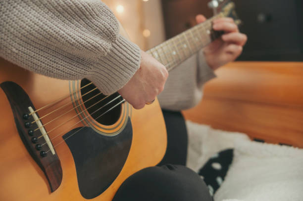istock A woman's hands playing guitar in a cozy bedroom. 1385440791