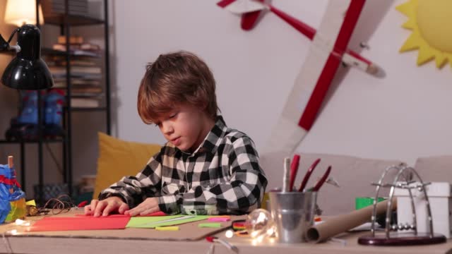 young boy folding a paper airplane and ships, causasian boy playing with paper airplanes, future engineer designer, hobby