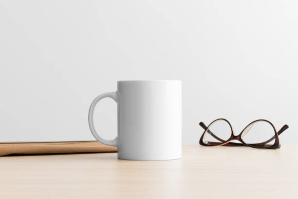 istock White mug mockup with workspace accessories on the wooden table. 1385447167