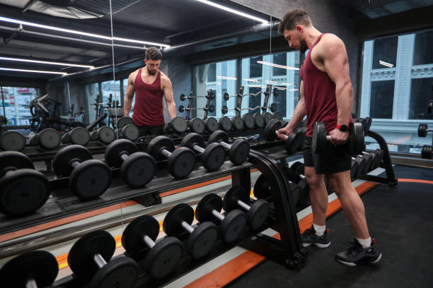 istock Healthy And Strong Man Lifting Weights With Dumbbells in Gym 1385461636