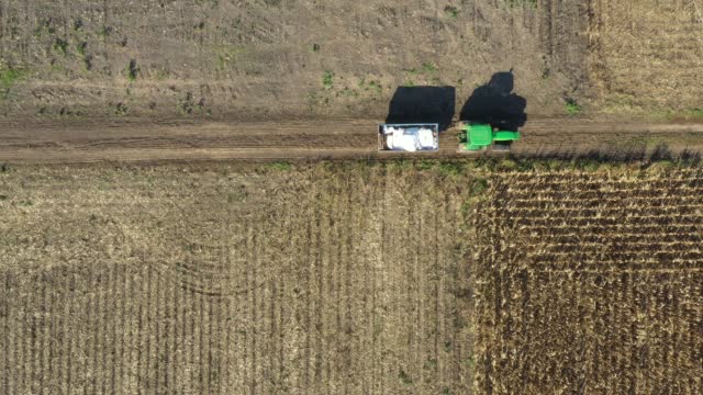 Aerial view of tractor with mounted trailer as travel on dirty road