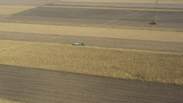 Aerial view of tractor with mounted trailer as travel on dirty road