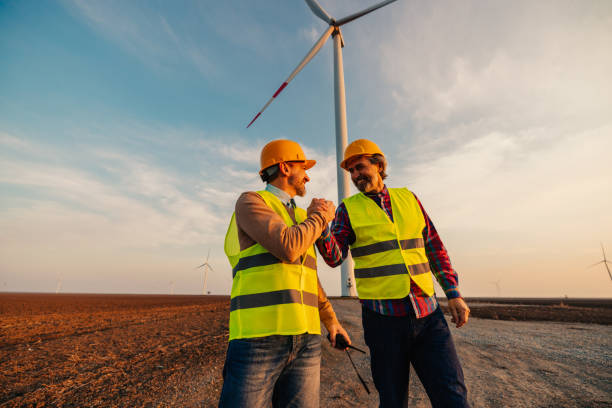 koledzy ściskający dłonie z turbinami wiatrowymi w tle - alternative energy electricity wind turbine team zdjęcia i obrazy z banku zdjęć