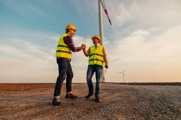 trabajo en equipo en campo con molino de viento - alternative energy electricity wind turbine team fotografías e imágenes de stock