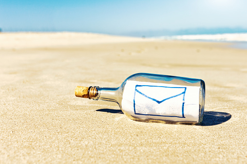 Retro-modern concept: email symbol written on the paper in a castaway's message in a bottle.