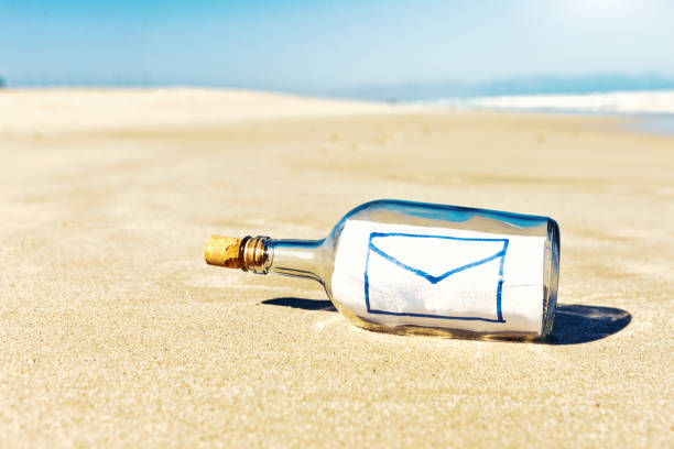 сообщение castaway в бутылке содержит символ конверта для электронной почты - message in a bottle beached bottle desert island стоковые фото и изображения