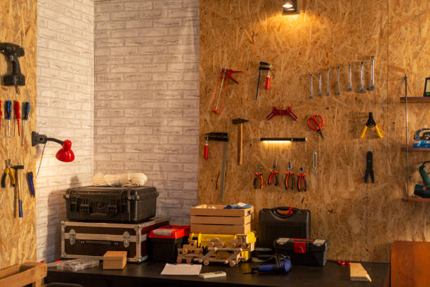 istock Artisan woodwork studio with shelving holding instruments, tools for carpentry and repair works. Empty workshop with Screwdriver, pliers and hammer hanging on board, workbench and toolbox. 1385471613