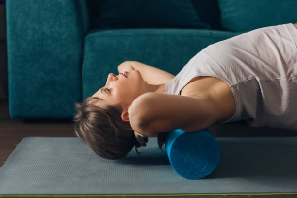 istock Working Out at Home: Fit Woman is Sportswear Using a Foam Roller 1385471941